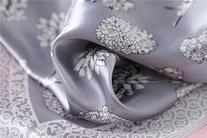 Close-up of elegant silver-grey silk scarf with white floral print and satin texture