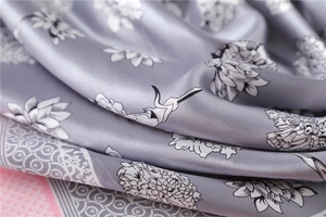 Detail of elegant silk scarf with grey lotus print and pink checkered border texture