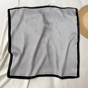 Close-up of geometric black and white striped silk scarf on white textured background