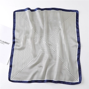 Flat lay of square silk scarf with geometric black white stripes and navy satin border