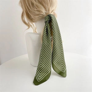 Detail of dark green striped silk scarf styled as an elegant hair accessory on braid