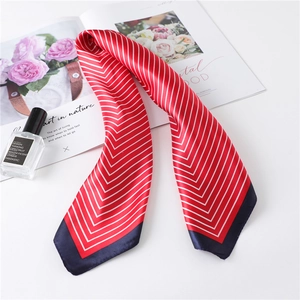 Detail of red silk scarf with white chevron stripes and navy border on a white table
