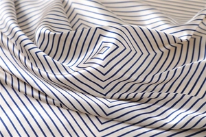 Macro shot of silk scarf fabric featuring elegant blue and white geometric stripes