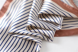 Close-up of elegant striped silk scarf featuring smooth satin texture and neat hemline