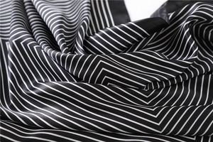 Close-up of black and white striped silk scarf showing smooth satin texture and geometric pattern
