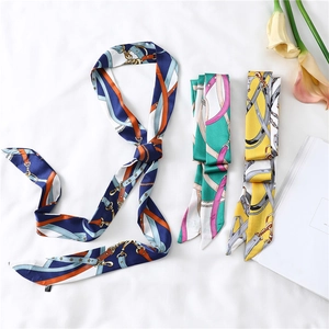 Flat lay of three narrow twilly scarves featuring horse harness and chain print patterns