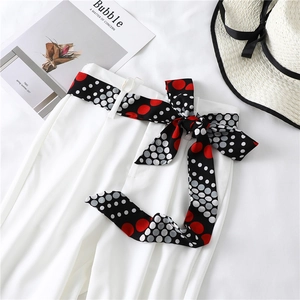 White high-waist trousers with a chic polka dot ribbon belt shown in a flat lay style