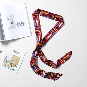 Detailed flat lay of a red chic skinny silk scarf with vintage chain and leather patterns
