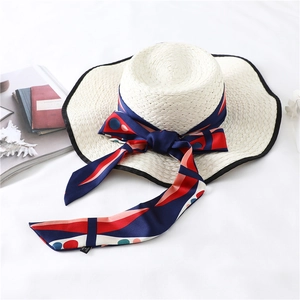 Flat lay of a white straw boater hat with navy polka dot ribbon and summer decor