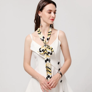 Detail showing white narrow silk scarf with black and yellow polka dot print tied as a knot