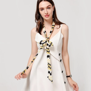 Close-up of a polka dot skinny scarf tied in a bow on a white sleeveless dress