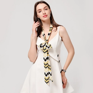 Detail of a polka dot narrow silk scarf tied in a bow on a white dress neckline