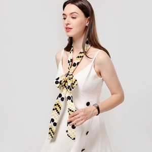 Close-up of yellow silk scarf with black polka dots tied elegantly on a white dress