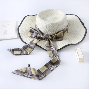 Detail of French vintage straw hat with checkered ribbon bow and elegant black edge trim