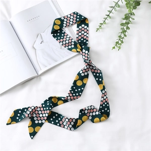 Close-up of a dark green narrow scarf with colorful polka dots on white bedding