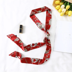 Detail of red narrow silk scarf featuring luxury gold chain patterns and vintage motifs