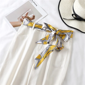 Chic yellow printed narrow silk scarf styled as a decorative belt on white trousers