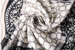 Macro shot of silk scarf with chain and floral patterns in elegant black and white colors