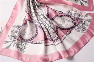Close-up of pink satin scarf with chain pattern and elegant bird print details
