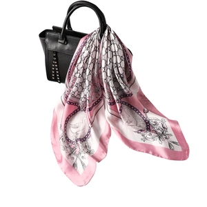Pink silk square scarf with chain patterns draped over a black leather handbag