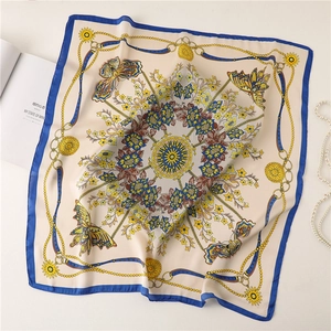 Close-up of elegant floral silk scarf with gold chain patterns and pearl necklace