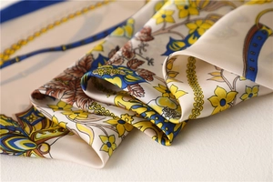 Detail of silk-texture square scarf with yellow flowers and golden chain patterns