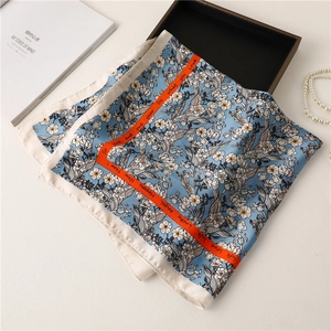 Macro detail of silk scarf with floral print and decorative orange border text