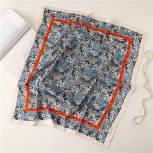 Close-up of blue floral square silk scarf with orange border and pearl necklace