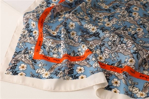 Macro detail of sky blue floral silk scarf with orange borders and elegant prints