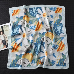 Detail of floral silk scarf with white daisy print and satin finish on dark background