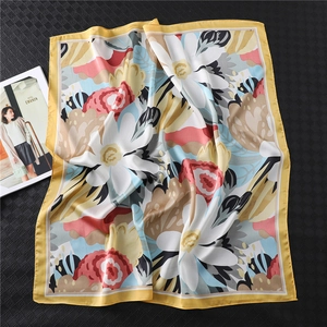 Elegant floral silk scarf with large white blossoms and yellow border on a textured background