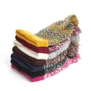 Detailed stack of colorful winter knit beanies featuring pom-poms and geometric patterns