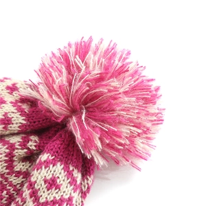 Close-up of fluffy two-tone pompom and geometric knit texture on a winter beanie hat