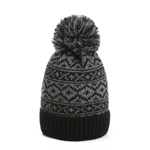 Macro detail of knit winter beanie with geometric diamond patterns and fuzzy pom-pom