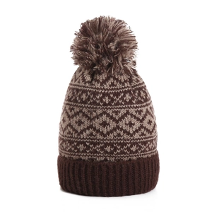 Close-up of brown knit beanie featuring diamond patterns and large faux fur pom-pom