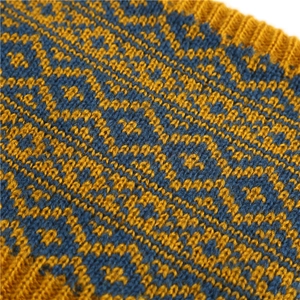 Macro detail of knit winter neck warmer with yellow and navy geometric rhombus pattern