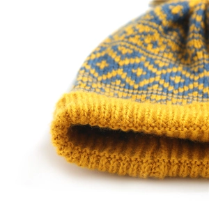Detail of yellow and blue knitted beanie featuring geometric jacquard pattern and thick ribbed cuff