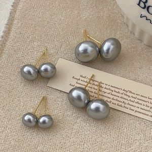 Detail of grey pearl earrings in four sizes on a vintage beige fabric background