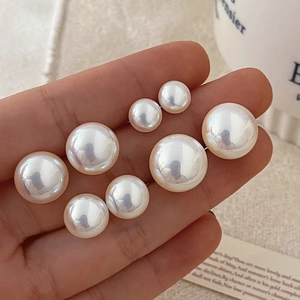 Elegant white pearl stud earrings in various sizes shown in a hand-held lifestyle setting