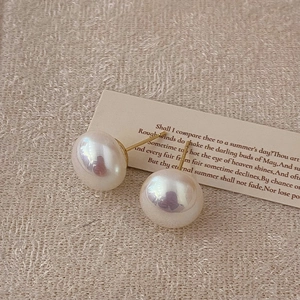 Detailed close-up of lustrous pearl stud earrings with gold hardware on a poetic card
