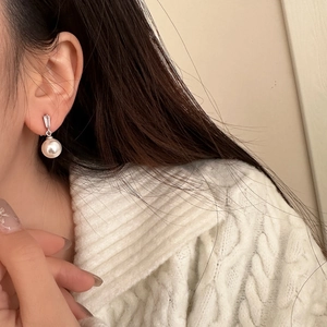 Elegant pearl drop earring with rectangular zircon on silver base worn by a model