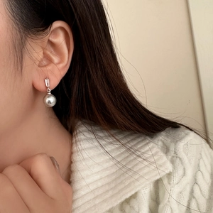 Close-up of pearl pendant earring with sparkling zircon on model in knitwear