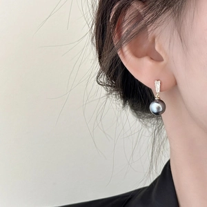 Detail of luxury drop earring with rectangle zircon and dark grey pearl on ear
