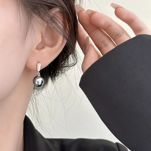 Close-up of elegant dark grey pearl drop earrings with rectangular zircon on model ear