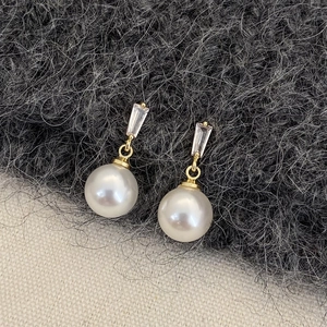 Detail of luxury pearl drop earrings with rectangular zircon and gold-plated frames