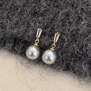 Detail of grey pearl earrings with gold metal links and rectangular clear zircon stones