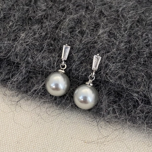 Detail of silver drop earrings with rectangular zircon and large grey pearl on fabric