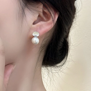 Elegant silver geometric earrings with white pearl pendants worn by a female model