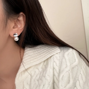 Detail of minimalist geometric pearl earring worn with a white cable-knit sweater