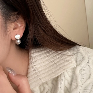 Close-up of minimalist silver pearl drop earring worn with a cozy white knit sweater